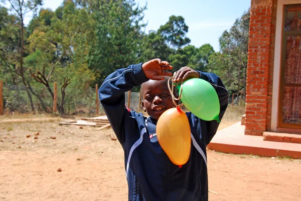 Un bambino africano gioca con palloncini colorati-Pomerini-Tanzania-A — Foto Stock