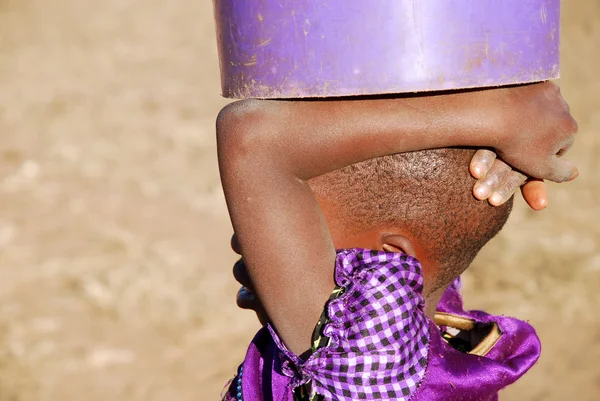 Un niño africano con un cubo de agua - Pomerini - Tanzania  - — Foto de Stock