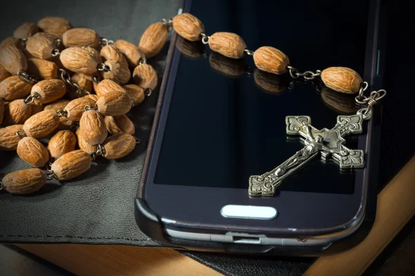 Smartphone crucifixo bíblico e contas de rosário — Fotografia de Stock