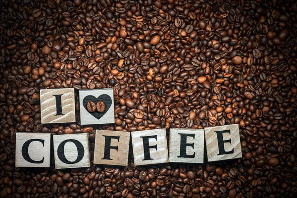 我喜欢咖啡 是用心形木块做的 背景是烤咖啡豆 — 图库照片