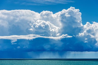 Güzel kümülüs bulutları (cumulonimbus) mavi gökyüzünde ve Akdeniz 'in üzerinde sağanak yağmur var. La Spezia Körfezi, Liguria, İtalya, Avrupa.