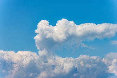 Açık mavi gökyüzünde kabarık beyaz bir bulutun yaklaşması, kümülonimbus. Fotoğraf, tam çerçeve.