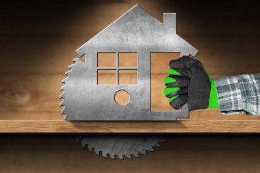 Marangoz koruyucu iş eldivenleriyle metal model ev şeklinde elektrikli testere kullanarak ahşap bir kalas kesiyor..