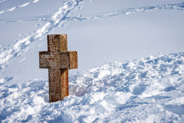 Древний каменный христианский крест в снегу на плато Лессиния (Altopiano della Lessinia). Malga San Giorgio, Bosco Chiesanuova, Verona province, Veneto, Italy, Europe.