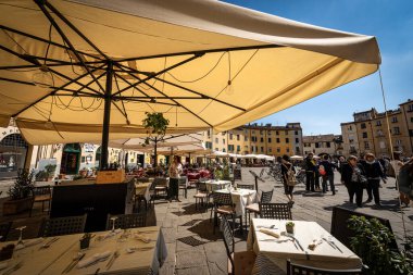 LUCCA, İtalya - 16 Nisan 2017: Lucca şehir merkezindeki Piazza dell 'Anfiteatro (Amfitiyatro Meydanı). Turistler ve yerliler antik eliptik şehir meydanını ziyaret ediyorlar. Toskana, İtalya, Avrupa.