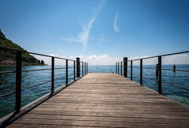 Garda Gölü 'nde (Lago di Garda), Veneto, İtalya, Güney Avrupa' da Verona ilinde küçük bir turizm beldesi olan Garda kasabasının önündeki küçük boş ahşap iskele..
