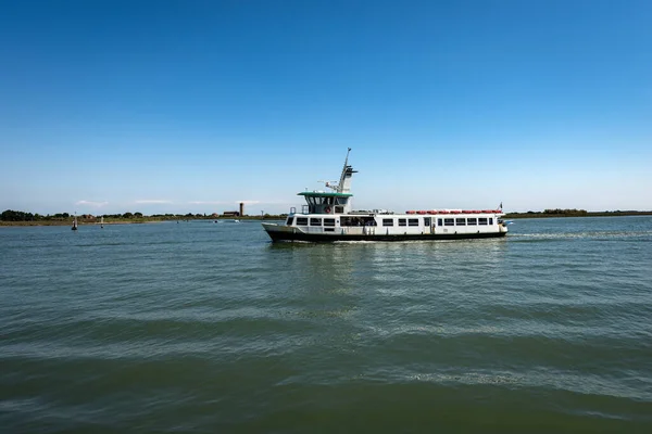 Ferry boat in motion in the Venice lagoon in front of Torcello and Burano island. On the horizon the Basilica and Cathedral of Santa Maria Assunta, UNESCO world heritage site, Veneto, Italy, Europe.