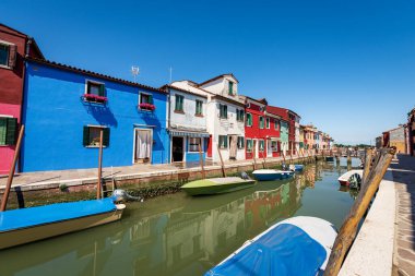 Güneşli bir bahar gününde Burano adasında çok renkli evler (parlak renkler) ve küçük tekneli bir kanal. Venedik lagünü, UNESCO dünya mirası sahası, Veneto, İtalya, Avrupa.