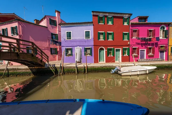 Burano island in the Venetian lagoon with multi colored houses (bright colors) and a canal with moored small boats in a sunny spring day. Venice, UNESCO world heritage site, Veneto, Italy, Europe.