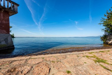 Garda Gölü (Lago di Garda), Verona ili, İtalya 'nın Veneto ili, güney Avrupa kıyısındaki küçük Lazise köyünden görülüyor. Arka planda Lombardy kıyısında.