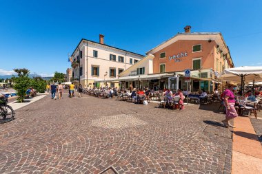 BARDOLINO, İtalya - 26 Mayıs 2021: Garda Gölü kıyısında (Lago di Garda) turist beldesi olan bir restoran ve pizzacı ile Bardolino köyü. Verona ili, Veneto, İtalya, Avrupa.