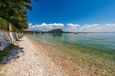 Garda Gölü 'nde (Lago di Garda) küçük bir kasaba olan Garda' nın önünde güzel bir sahil. San Vigilio (Punta San Vigilio), Verona, Veneto, İtalya, Avrupa. Ufukta Rocca di Garda var..