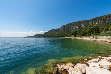 Garda Gölü kıyısındaki küçük Garda kasabasının önündeki sahil şeridi (Lago di Garda). San Vigilio Burnu (Punta San Vigilio) ile güzel bir körfez. Verona, Veneto, İtalya, Avrupa