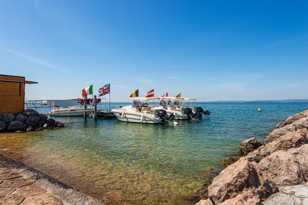 Group of small motor boats for rent in Lake Garda, small port of Cisano village, tourist resort, Bardolino municipality, Verona province, Veneto, Italy, southern Europe. Lombardy coast on the horizon.