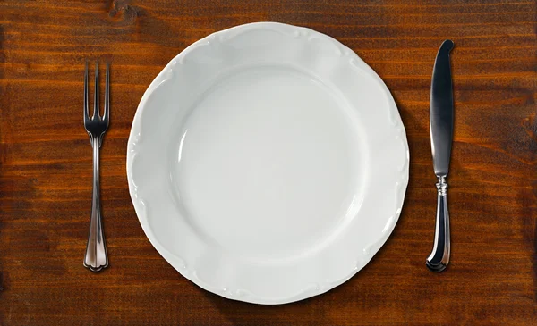 Άδειο πιάτο στο ξύλινο τραπέζι με τα μαχαιροπήρουνα — Φωτογραφία Αρχείου
