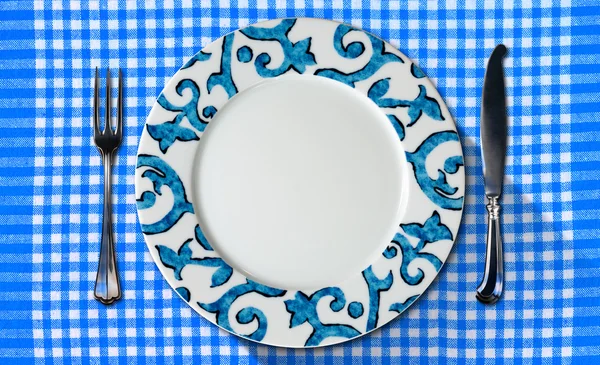 Пустая тарелка на скатерти со столовыми приборами — стоковое фото