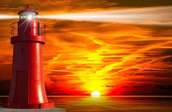 Phare rouge avec faisceau lumineux au coucher du soleil — Photo