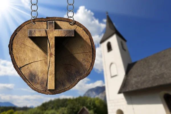 Dřevěný kříž na kmen stromu s kostelík — Stock fotografie