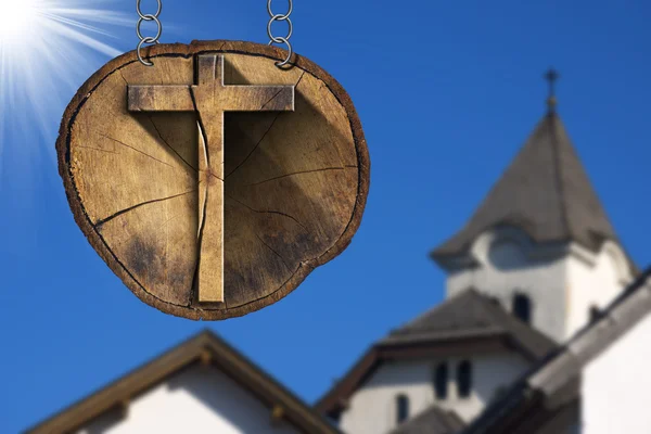 Деревянный крест на стволе дерева с церковью — стоковое фото