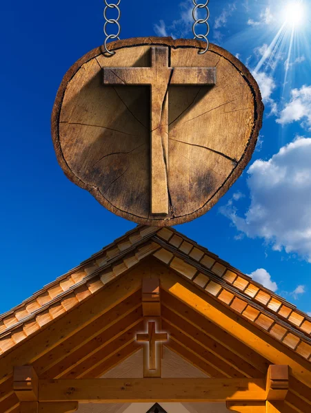 Kříž na kmen stromu s dřevěný kostel — Stock fotografie