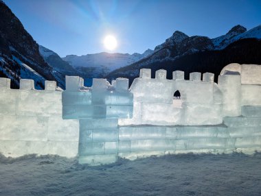 Buz kalesi buz tuğlalarından, şeffaf mavi gölgeler güneşte parlar Rocky Dağları 'nın arka planında karla kaplı - güneşli bir günde kış eğlencesi, Louise Gölü, Alberta, Kanada