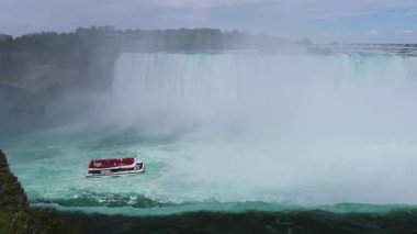 Niagara Şelalesi - At nalı Şelalesinin Kıyısı - mavi su uçurumun kenarından akıyor, turistlerle dolu bir yolcu gemisi, Niagara Şelalesi, Ontario, Kanada 'da eğlence sektörüne yakın bir yere geldi..