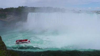 Niagara Şelalesi - At nalı Şelalesinin Kıyısı - mavi su uçurumun kenarından akıyor, turistlerle dolu bir yolcu gemisi, Niagara Şelalesi, Ontario, Kanada 'da eğlence sektörüne yakın bir yere geldi..