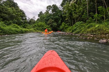Kano ve kano, Tayland 'daki tropikal ormanlarda rafting yapıyor. Tayland, adrenalin arayanlar ve doğa severler için rafting cennetidir. Renkli can yeleğiyle donatılmış kano sürücülerinin etkinliği.