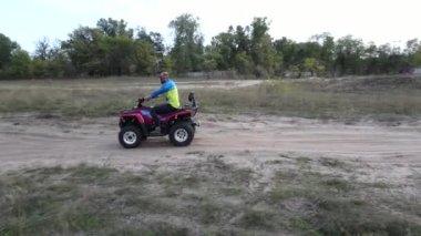 Üç adam çölde kumlu yolda bisiklet sürüyor..