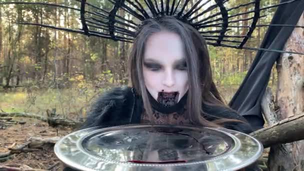若い女性の肖像画で黒のドレスと王冠で彼女の頭の上に血の顔と血と皿 — ストック動画