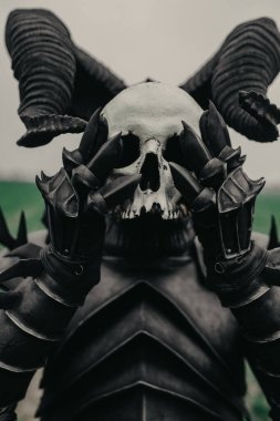 Mutant savaşçı elinde insan kafatası görüntüsüyle maske tutuyor..