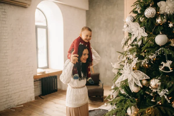 幸せな母親とともに彼女の息子の遊びと楽しみますクリスマスツリーの近くに装飾付き — ストック写真
