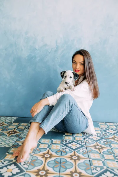 Genç Bir Kadın Mavi Arka Planda Elinde Dalmaçyalı Köpek Yavrusuyla — Stok fotoğraf