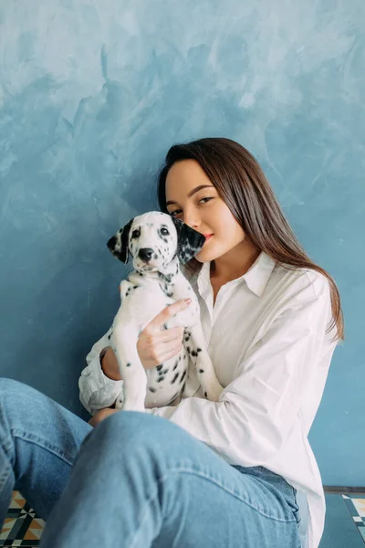 Young Woman Sits Puppy Dalmatian Dog Her Hands Blue Background — Stock Photo, Image