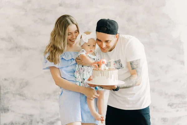 Young parents give birthday cake for the first year of birth their little daughter.