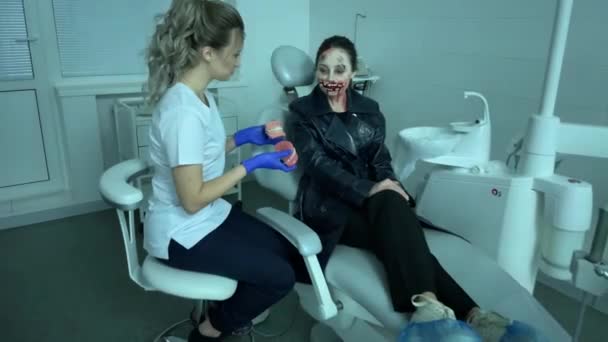 醜い血液変異体のイメージの女性は 現代の歯科クリニックで椅子に座っています 医者は彼女の歯の印象を示す 点滅する光 コスプレ — ストック動画