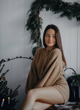 Genç bir kadın elinde süslerle Noel ağacının yanındaki odada oturuyor. Yakın çekim..