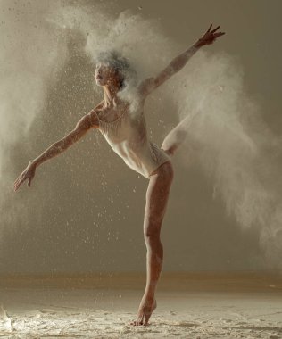 Japon balerin, zeminde beyaz un bulutunun arka planına karşı arabesk pozu veriyor..