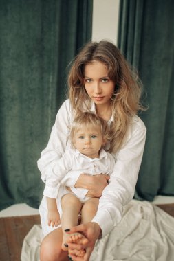 Mutlu genç anne oturur ve küçük oğlunu kucağına alır ve ona sarılır..