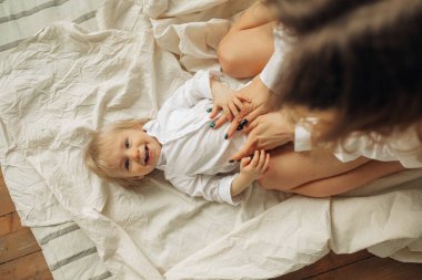 Mutlu genç anne eğleniyor ve küçük oğluyla oynuyor..