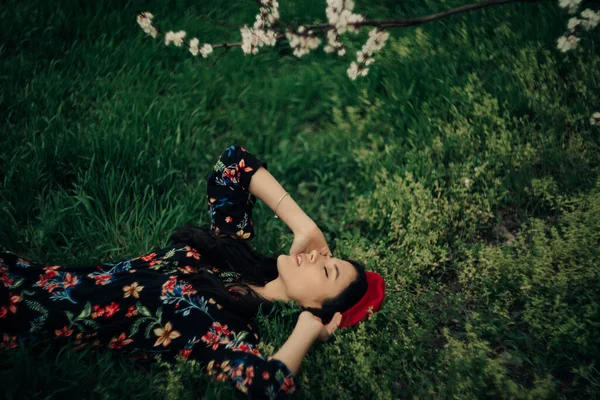Young Brunette Woman Lies Grass Garden Spring Blossoming Apricot Trees — 스톡 사진