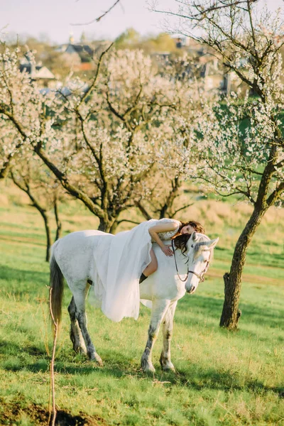 Novia Vestido Blanco Largo Sienta Caballo Caballo Blanco Abraza Jardín — Foto de Stock