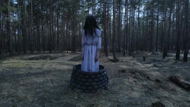怖いゴーストゾンビのイメージで長い黒い髪の女の子は森の中の石の中によく立っています ハロウィンのコンセプト — ストック動画