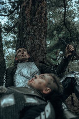 İki yorgun ortaçağ savaşçısı zırhlı şövalyeler ağacın altında dinleniyor..