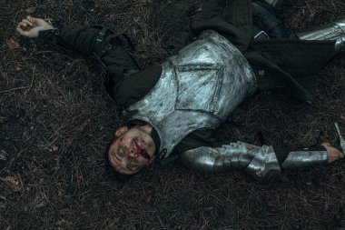 Ortaçağ savaşında zırhlı bir şövalye olarak yenilgiye uğrayan ormanın ortasında, savaş alanında yatıyor. Üst görünüm.