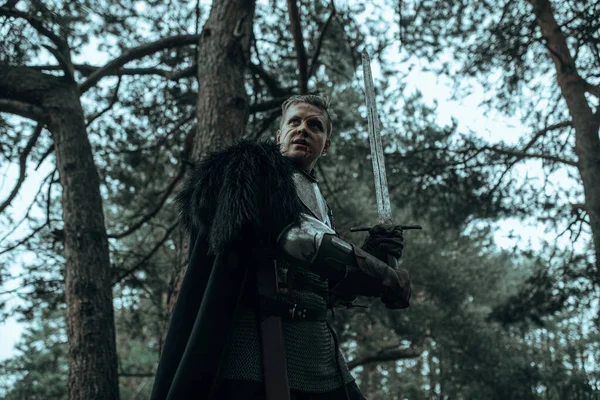 身穿链甲和黑色斗篷的中世纪武士骑士站在森林中 手里拿着一把高剑 — 图库照片