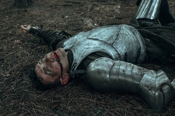 战败的中世纪骑士身穿盔甲躺在森林中的战场上 — 图库照片