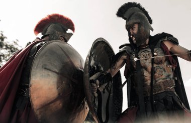 İki antik Yunan ya da Roma savaşçısı arasındaki savaş elbisesi ile gökyüzü arka planında.