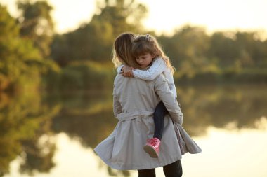 Anne kızıyla birlikte nehir kenarındaki parkta yürüyor..