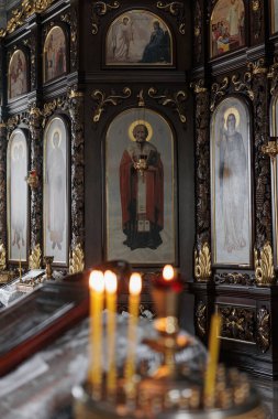 Merkezi aziz ikonu olan ortodoks kilise ikonası. Bulanık, parlak mumlar ön planda karanlık, kutsal, ruhsal atmosfer yaratır..